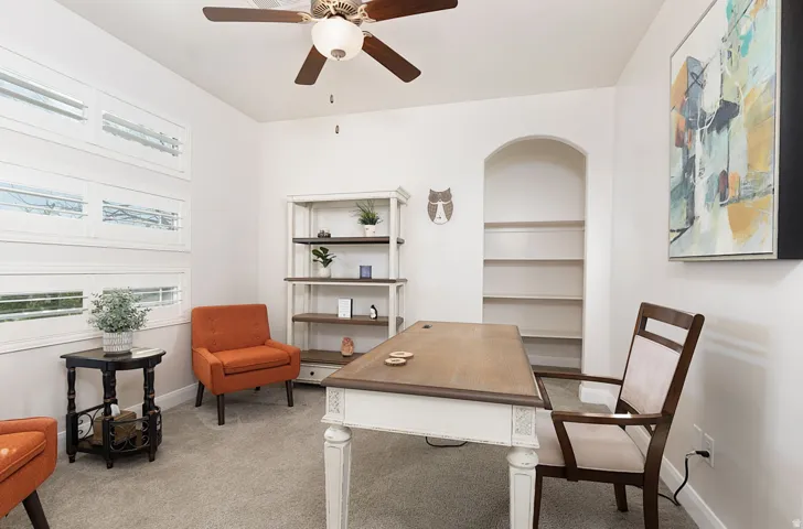 Office space featuring a ceiling fan and light colored carpet