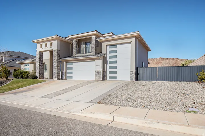 Contemporary house with stone siding, stucco siding, a garage, a balcony, and concrete driveway