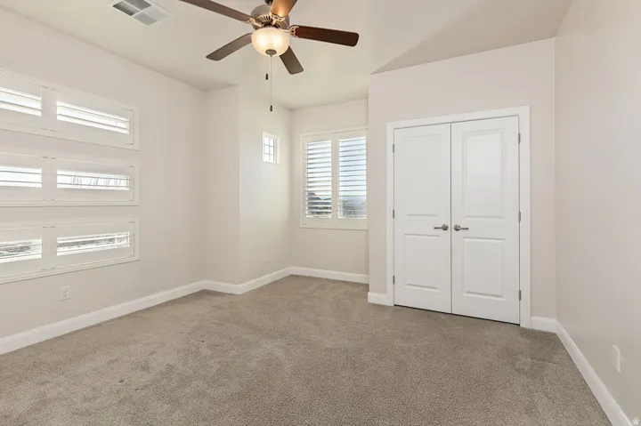 Unfurnished bedroom featuring light carpet, ceiling fan, and a closet