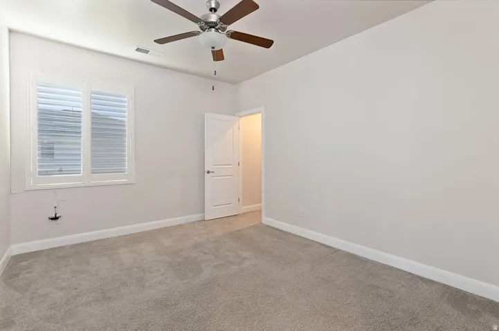Empty room with light colored carpet and ceiling fan