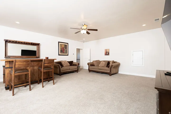 Living area with light carpet, ceiling fan, and recessed lighting