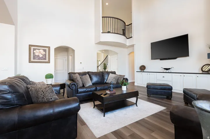 Living room featuring arched walkways, wood finished floors, and a high ceiling