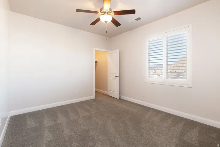 Carpeted spare room with baseboards and a ceiling fan