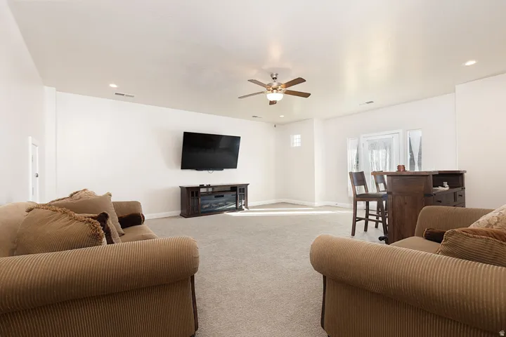 Living area with light carpet, ceiling fan, and recessed lighting