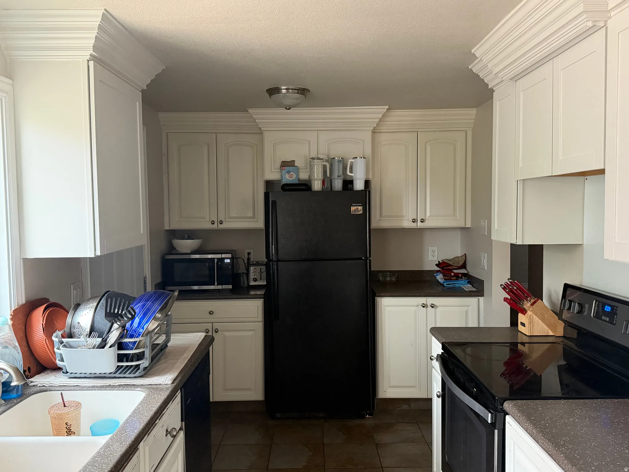 Kitchen featuring black appliances, dark tile patterned flooring, white cabinets, and dark countertops