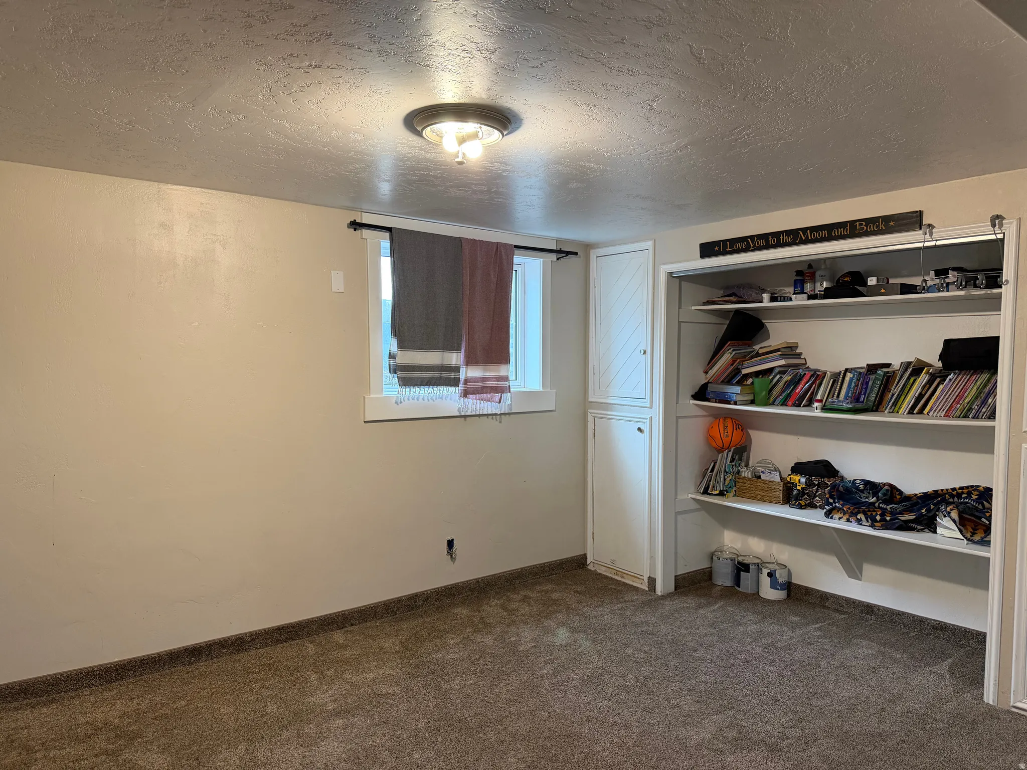 Bedroom with a textured ceiling, dark colored carpet, and a closet