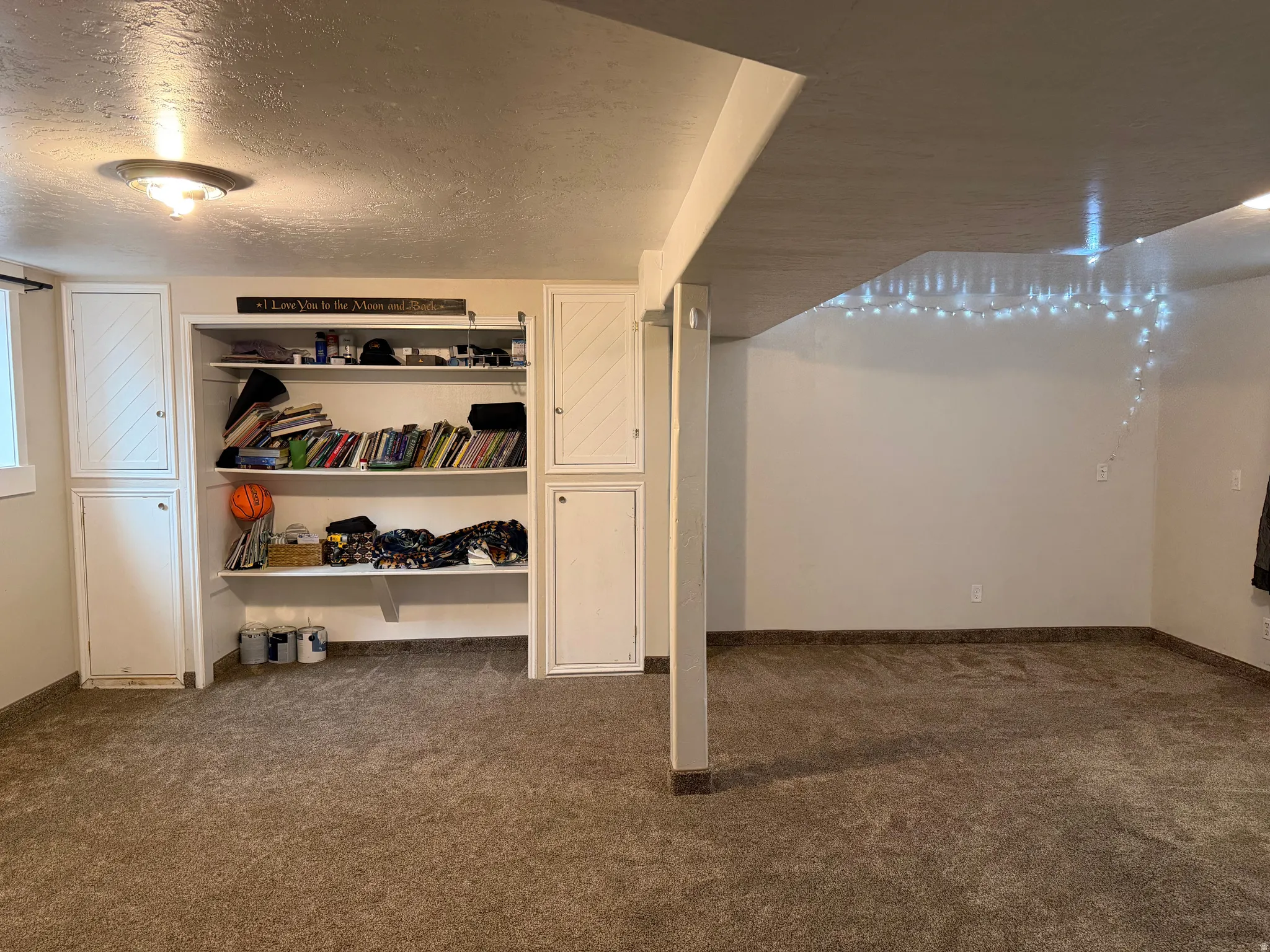 Finished below grade area with a textured ceiling and dark colored carpet