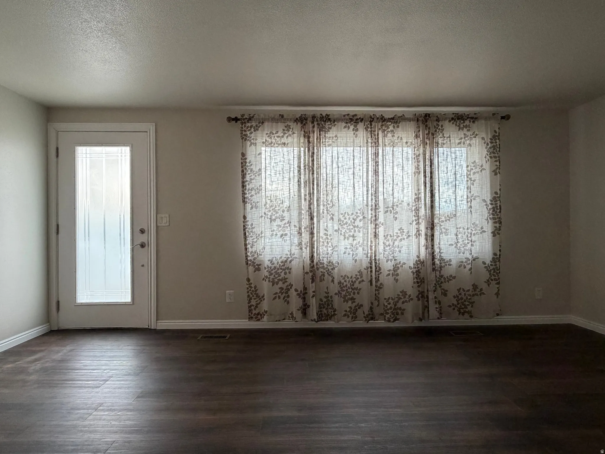 Unfurnished dining area featuring a textured ceiling and dark wood-type flooring