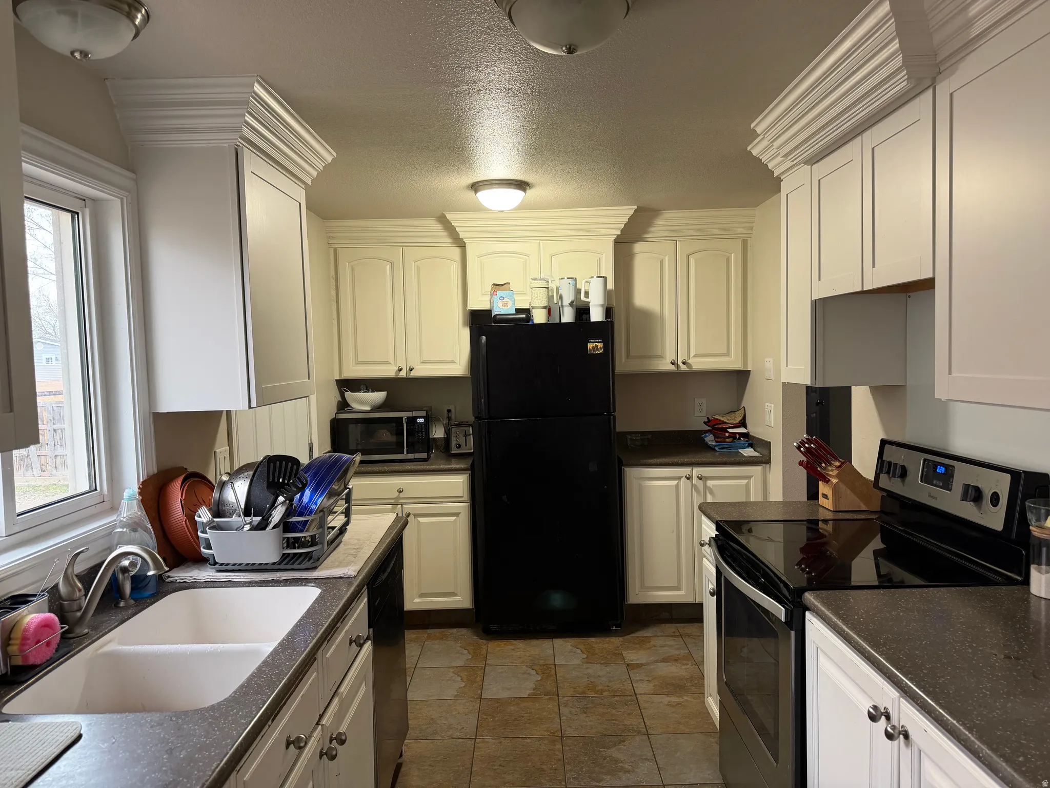 Kitchen featuring stainless steel appliances, white cabinetry, and a textured ceiling