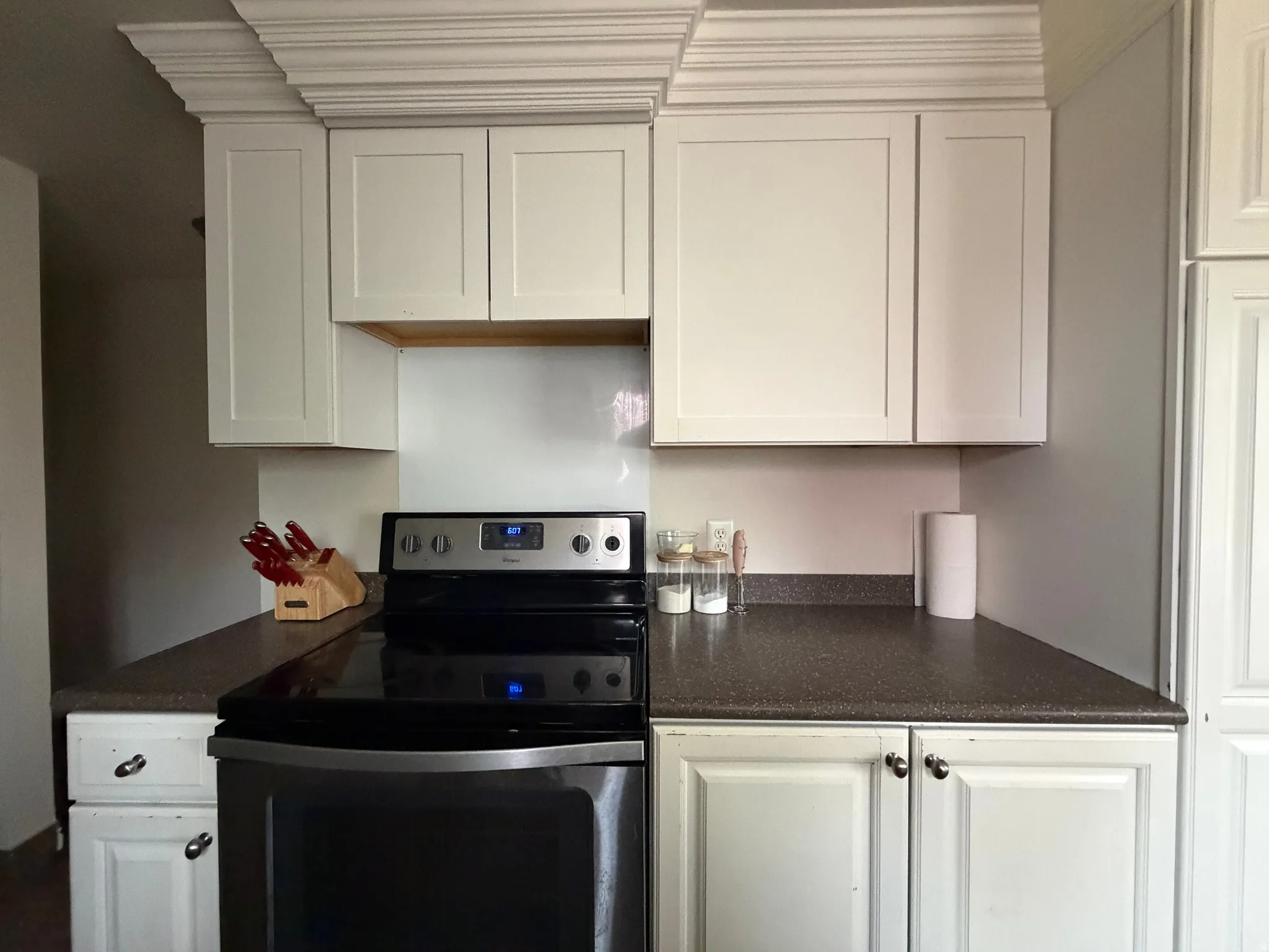Kitchen with electric stove and white cabinets