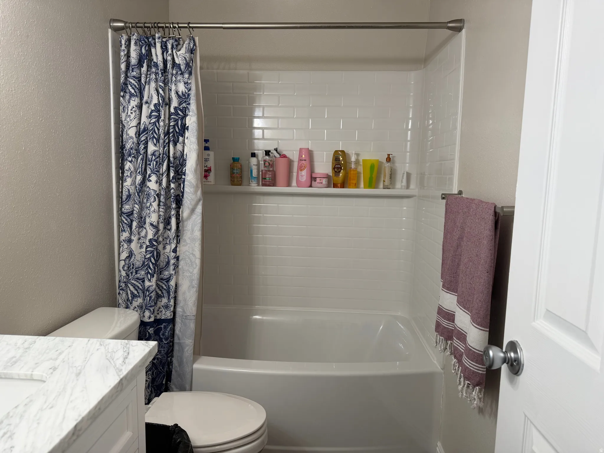 Full bathroom with vanity, a textured wall, and shower / bathtub combination with curtain