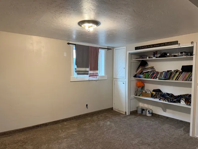 Bedroom with a textured ceiling, dark colored carpet, and a closet
