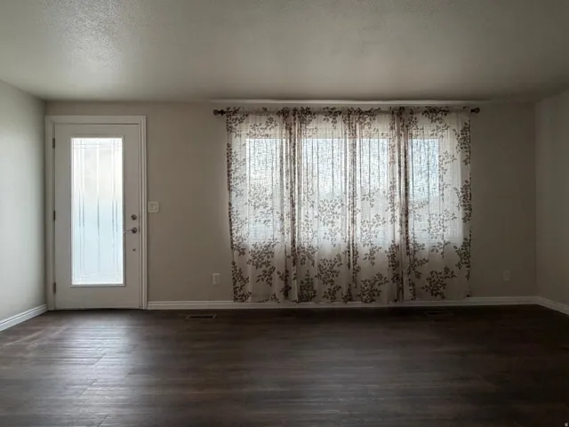 Unfurnished dining area featuring a textured ceiling and dark wood-type flooring