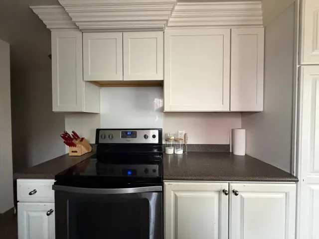 Kitchen with electric stove and white cabinets
