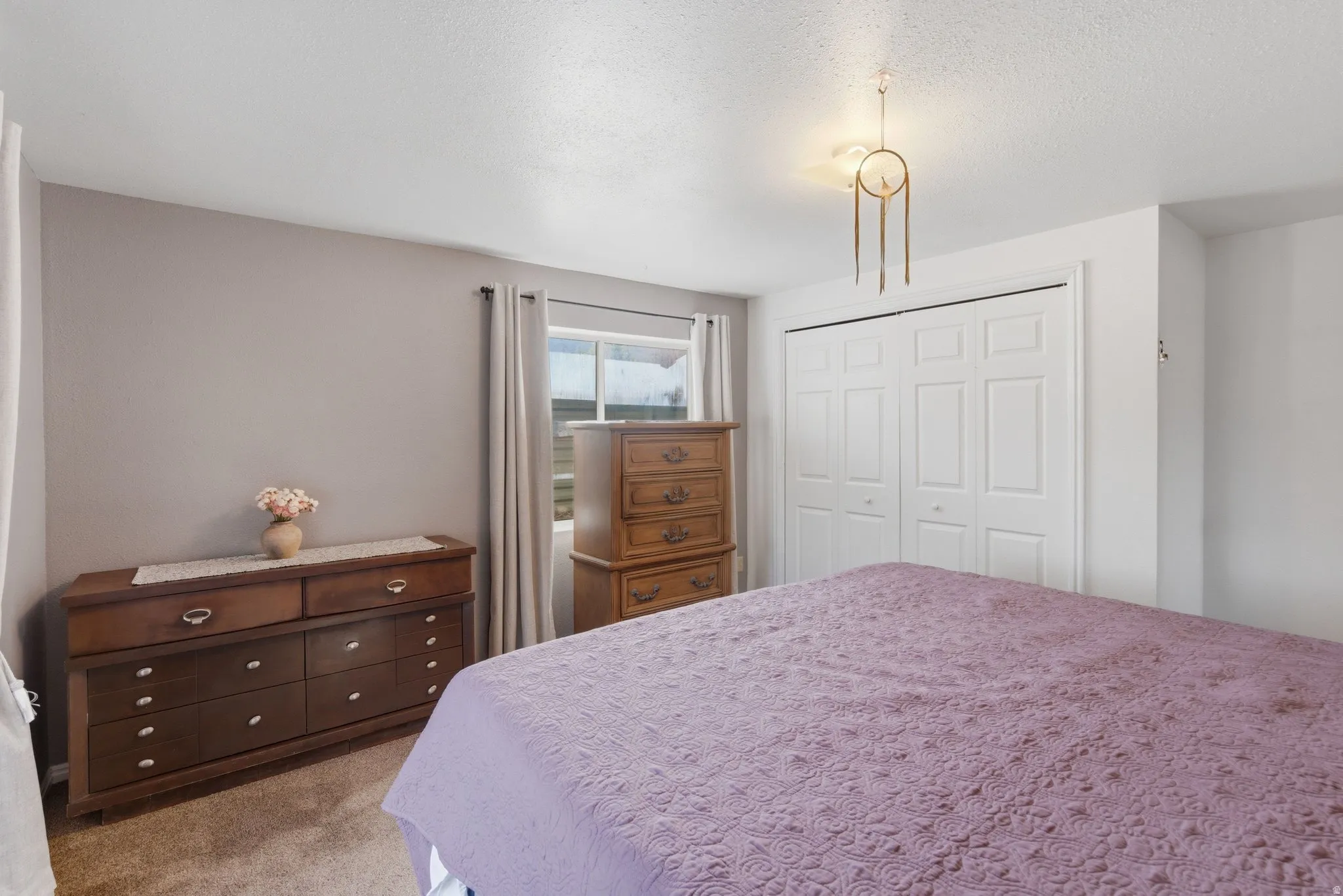 Bedroom with a closet, light carpet, and a textured ceiling