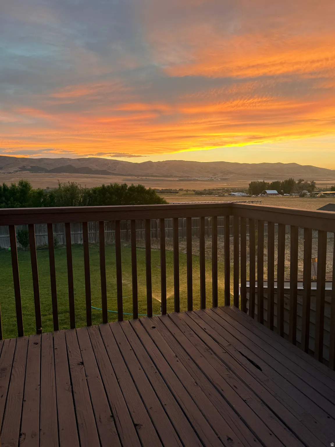 Private deck with wood decking and railing overlooking a spacious backyard and distant mountains
