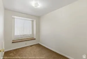 Recessed window with wood-finish sill, brown carpeting, and white baseboards