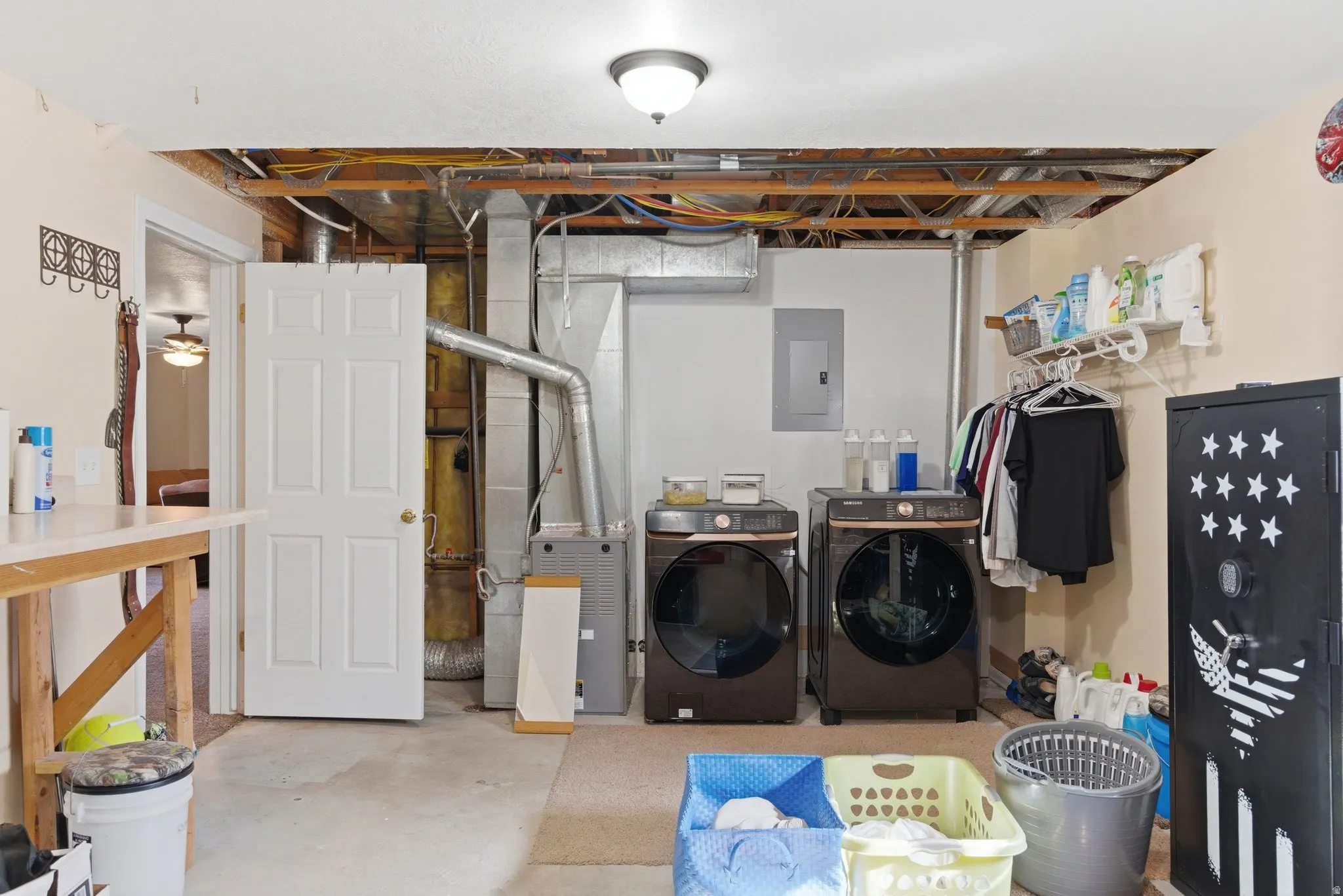 Laundry room with concrete flooring, washing machine and dryer, electric panel, and heating unit