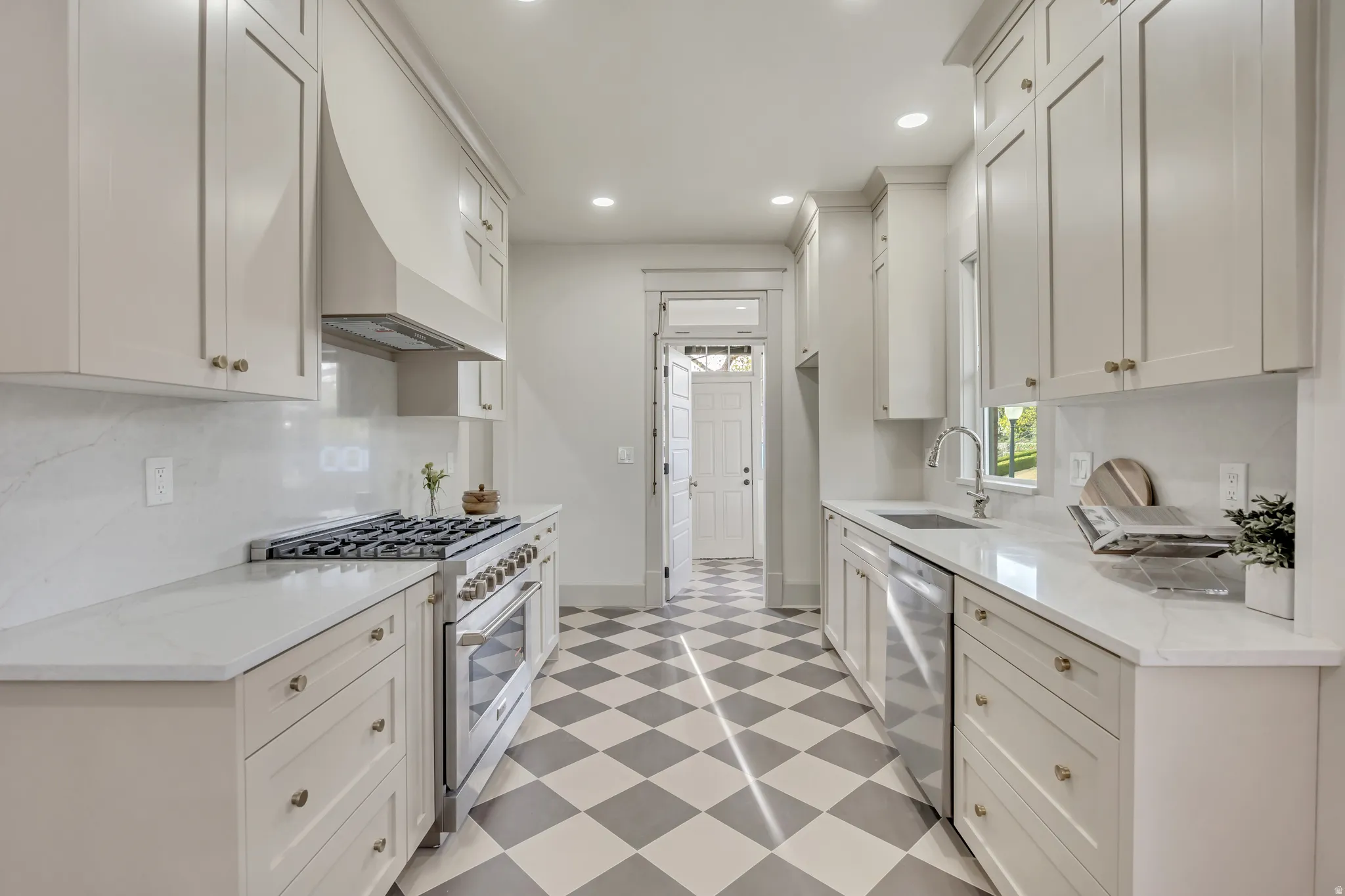 Kitchen with light floors, stainless steel appliances, light stone counters, white cabinets, and recessed lighting