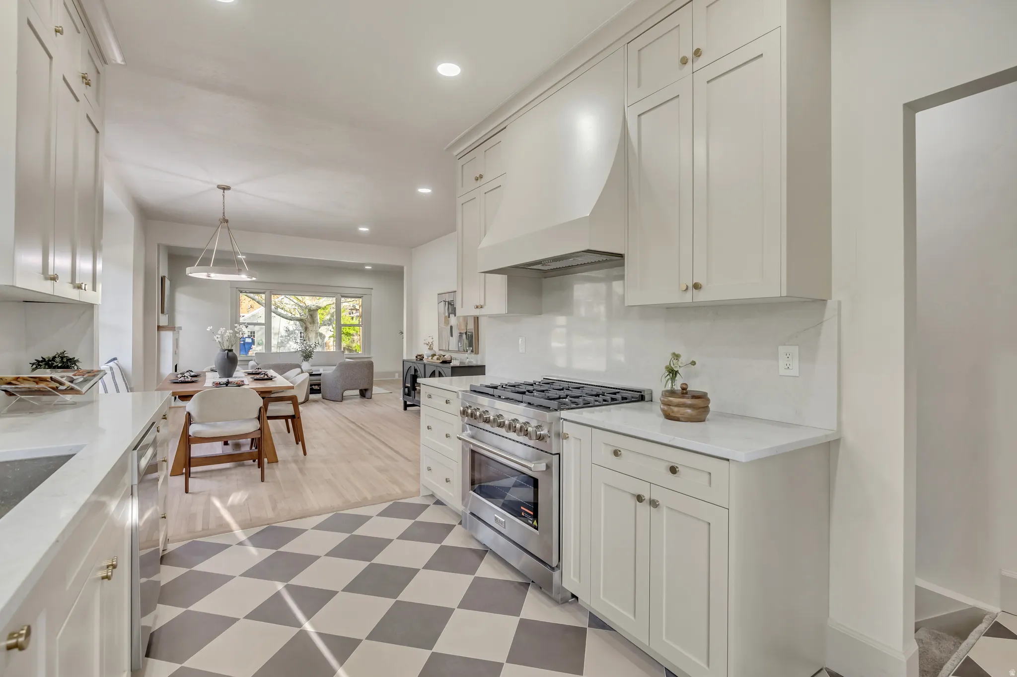 Kitchen with stainless steel appliances, white cabinetry, light stone countertops, and light flooring