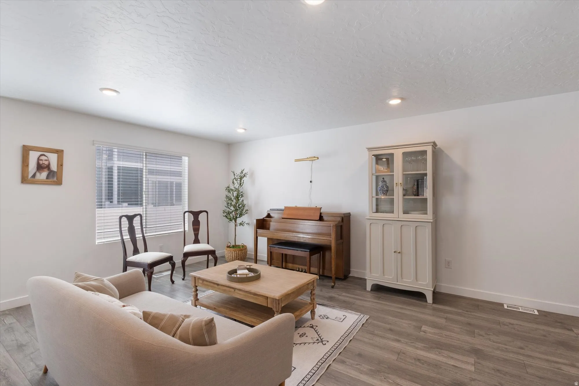 Living room featuring a textured ceiling, wood finished floors, and recessed lighting