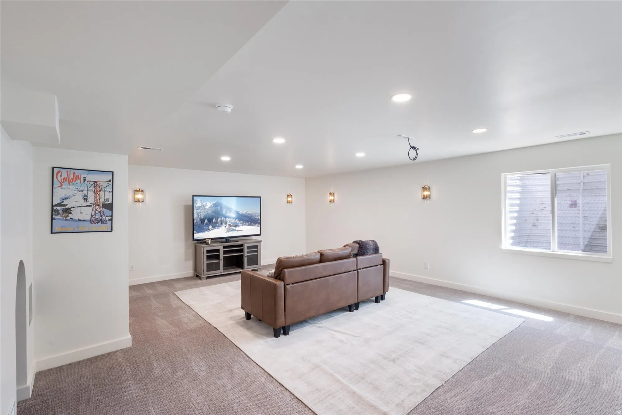 Living area with light carpet and recessed lighting