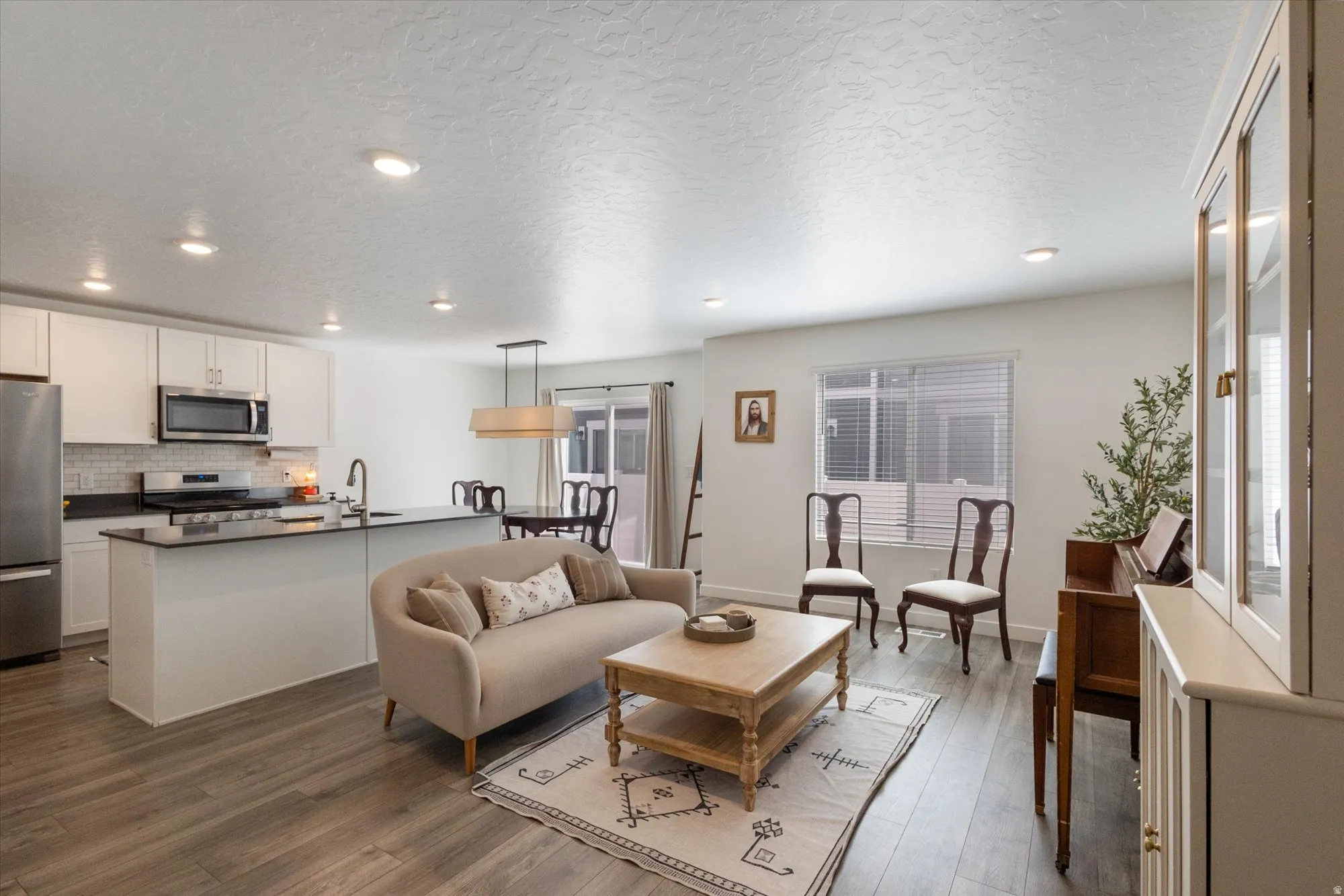 Living room with dark wood-style floors, a textured ceiling, and recessed lighting