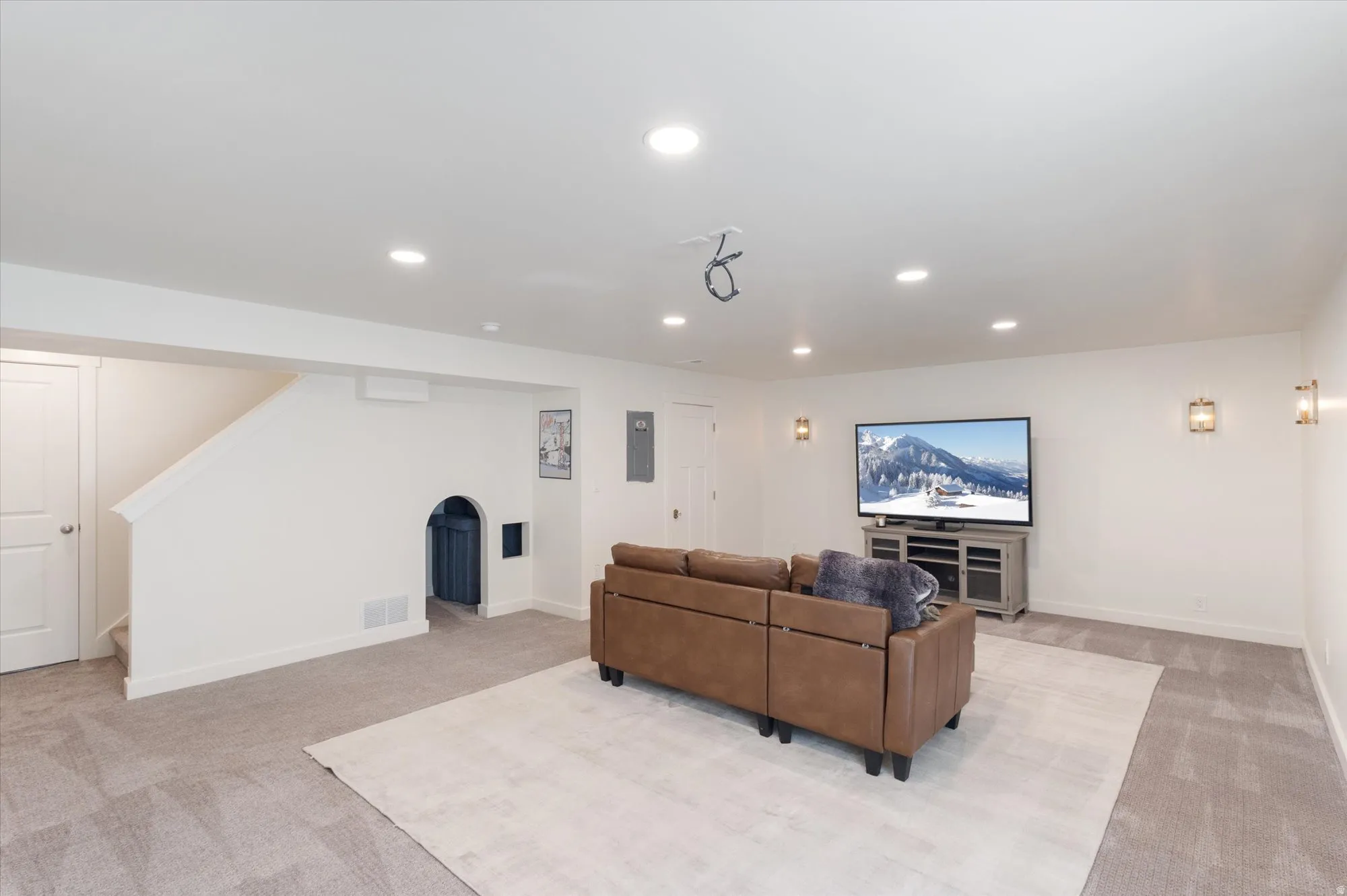 Living area with light colored carpet, recessed lighting, arched walkways, and electric panel