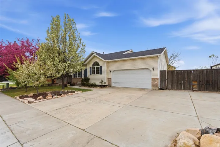 View of front of property with an attached garage, driveway, brick siding, and a gate