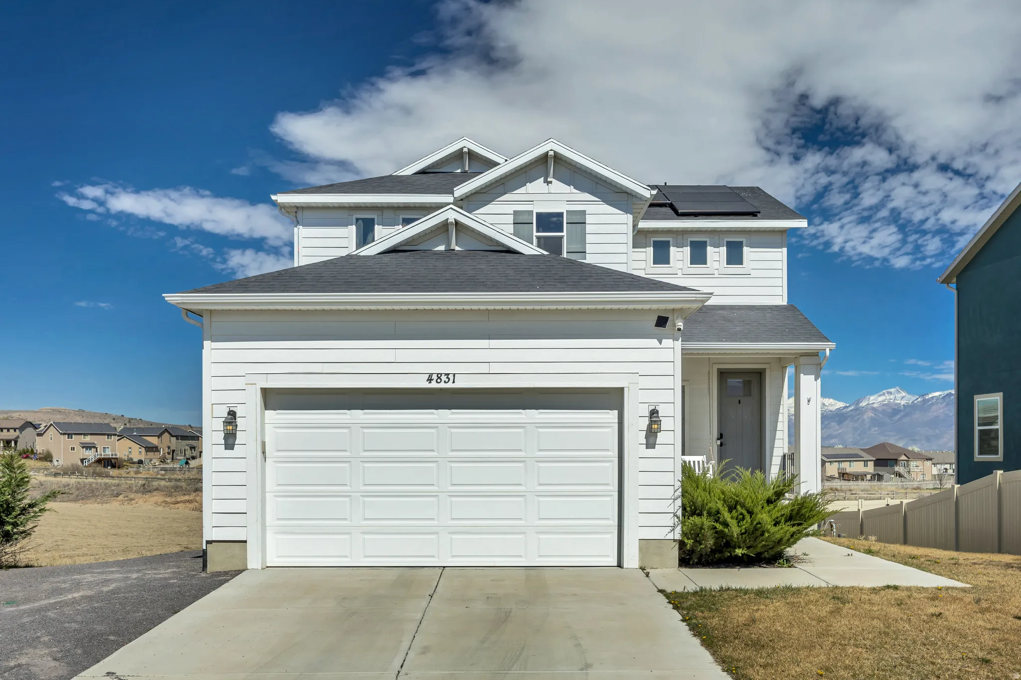View of front of property featuring solar panels, a mountain view, driveway, a garage, and a shingled roof