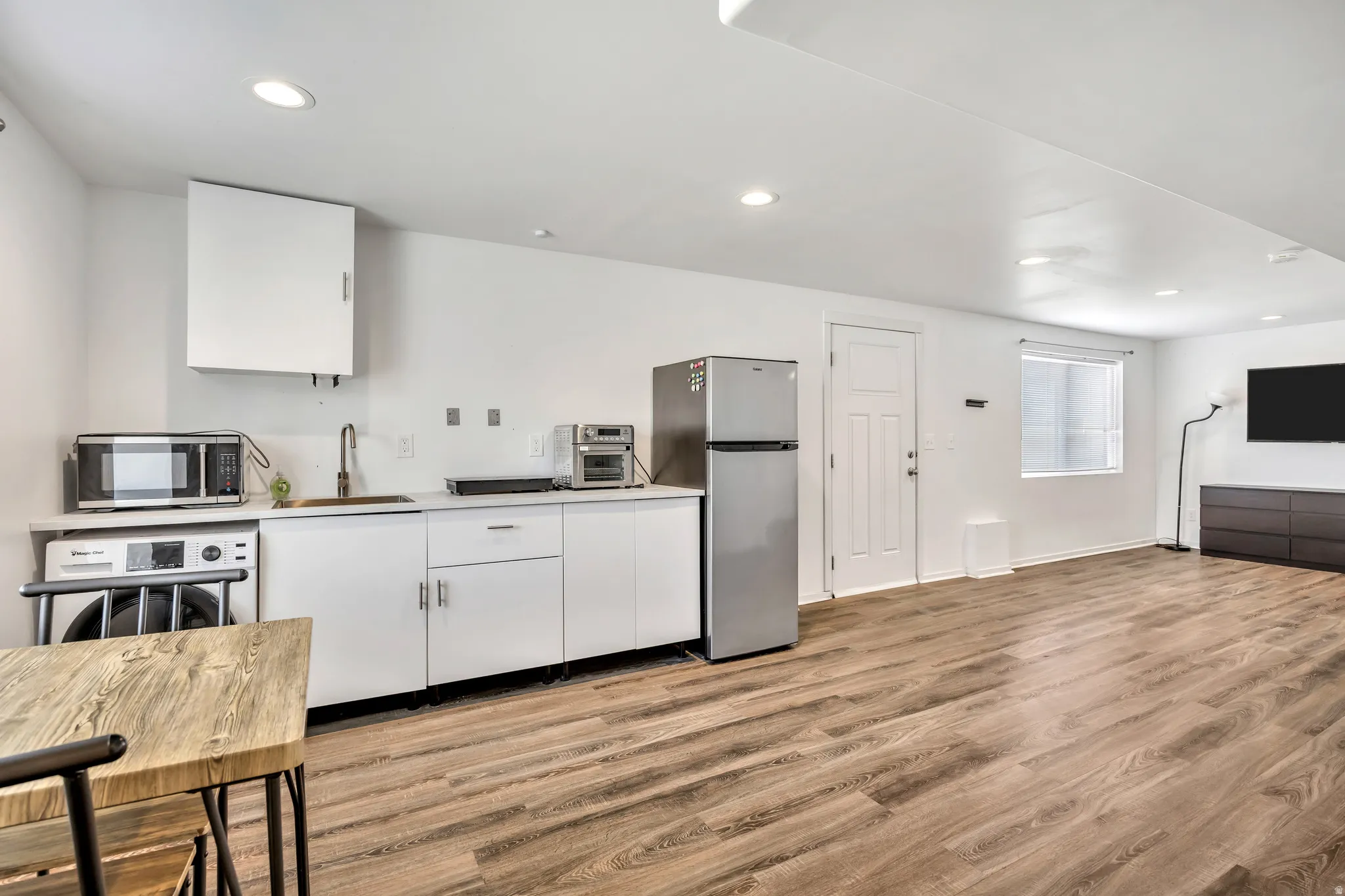 Kitchen featuring white cabinets, light countertops, stainless steel appliances, recessed lighting, and light wood-type flooring