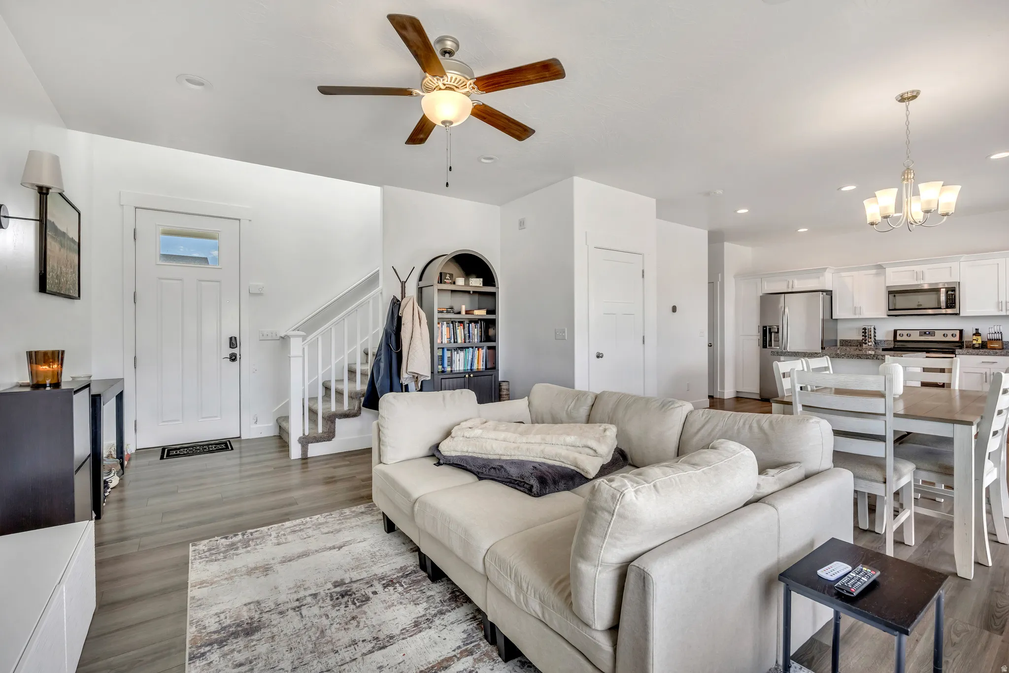 Living room with ceiling fan, dark wood finished floors, and a chandelier