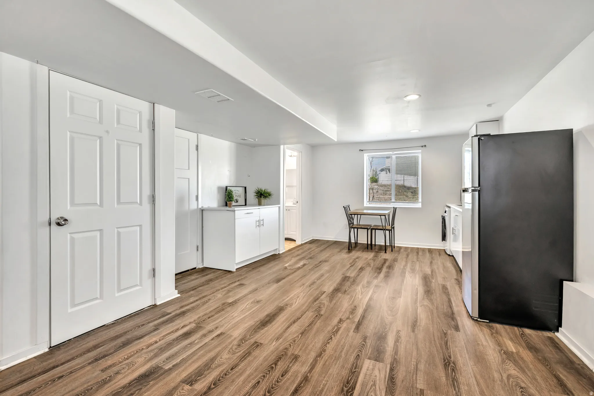 Kitchen featuring freestanding refrigerator, white cabinetry, light countertops, and light wood-style floors