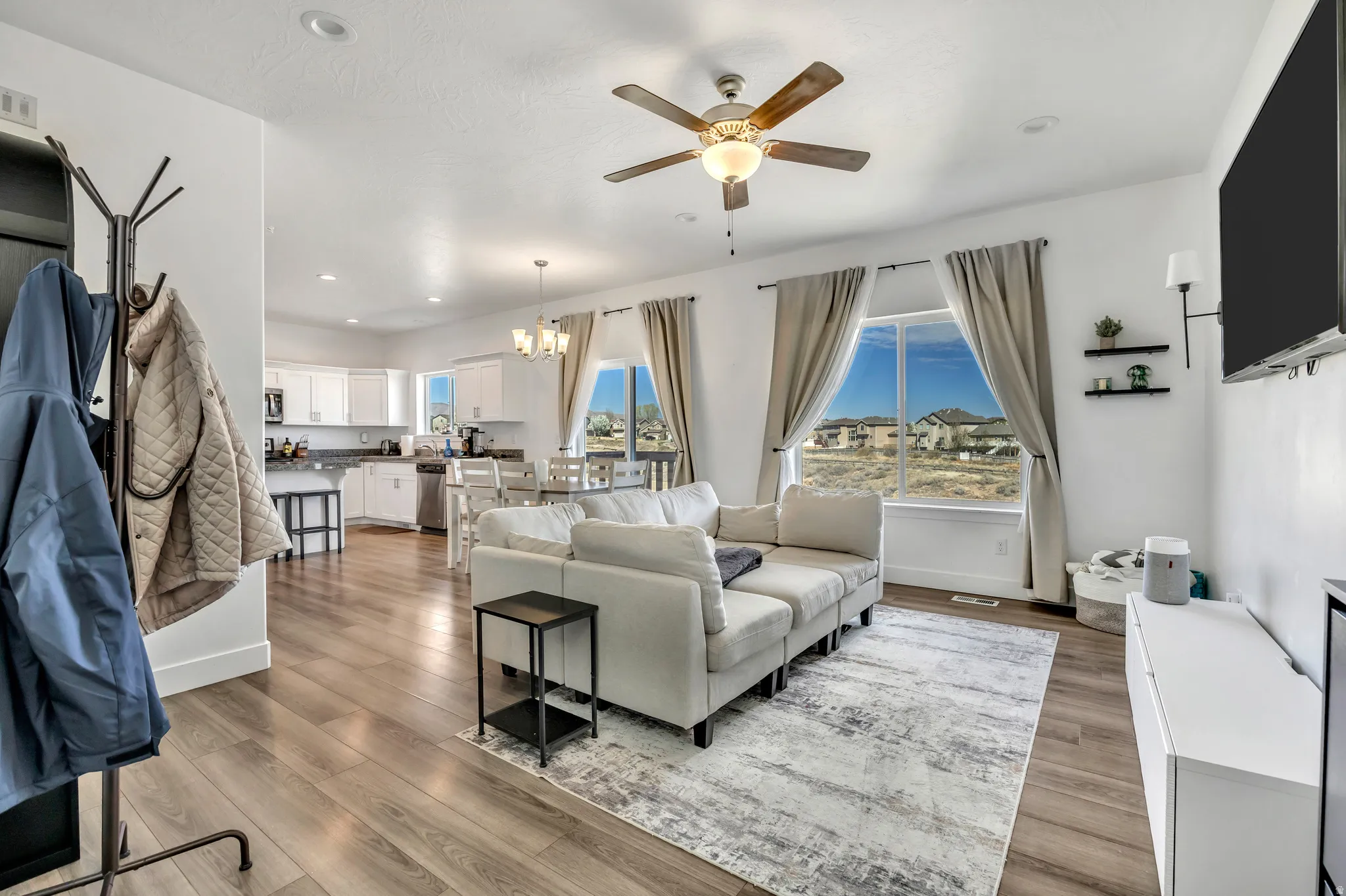 Living room with a chandelier, light wood-style flooring, a ceiling fan, and healthy amount of natural light