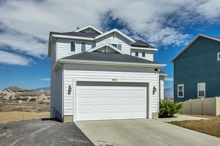 View of front of property featuring driveway, roof mounted solar panels, and a garage
