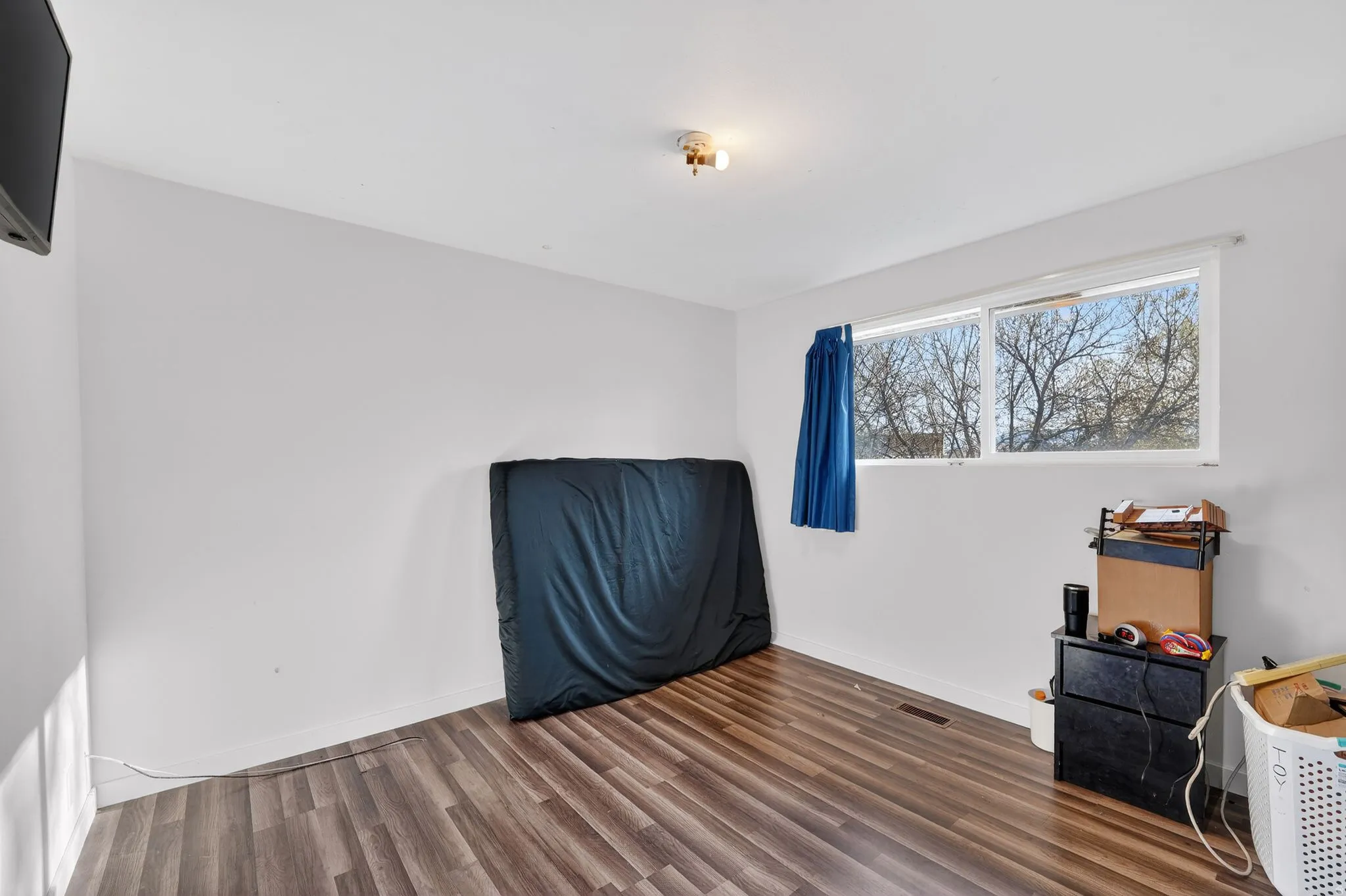 Bedroom with laminate finished floors and baseboards
