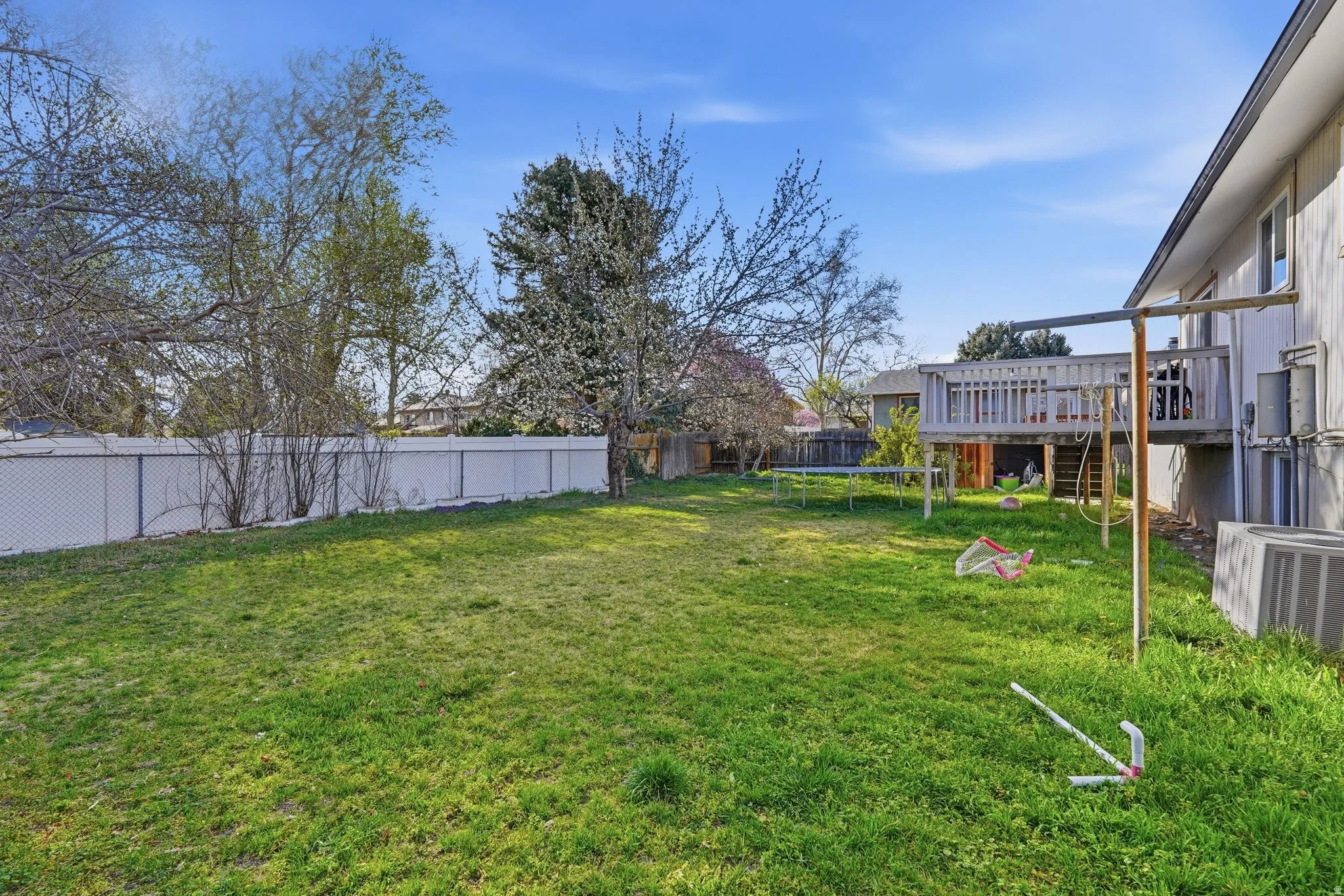 Fenced backyard with a trampoline and a deck