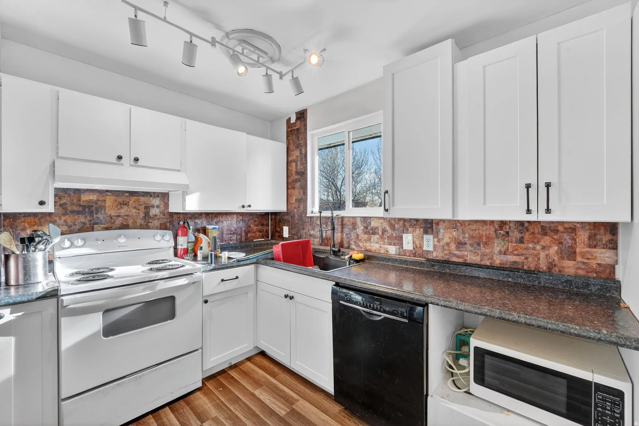 Kitchen featuring white cabinetry, electric range, dishwasher, and track lighting
