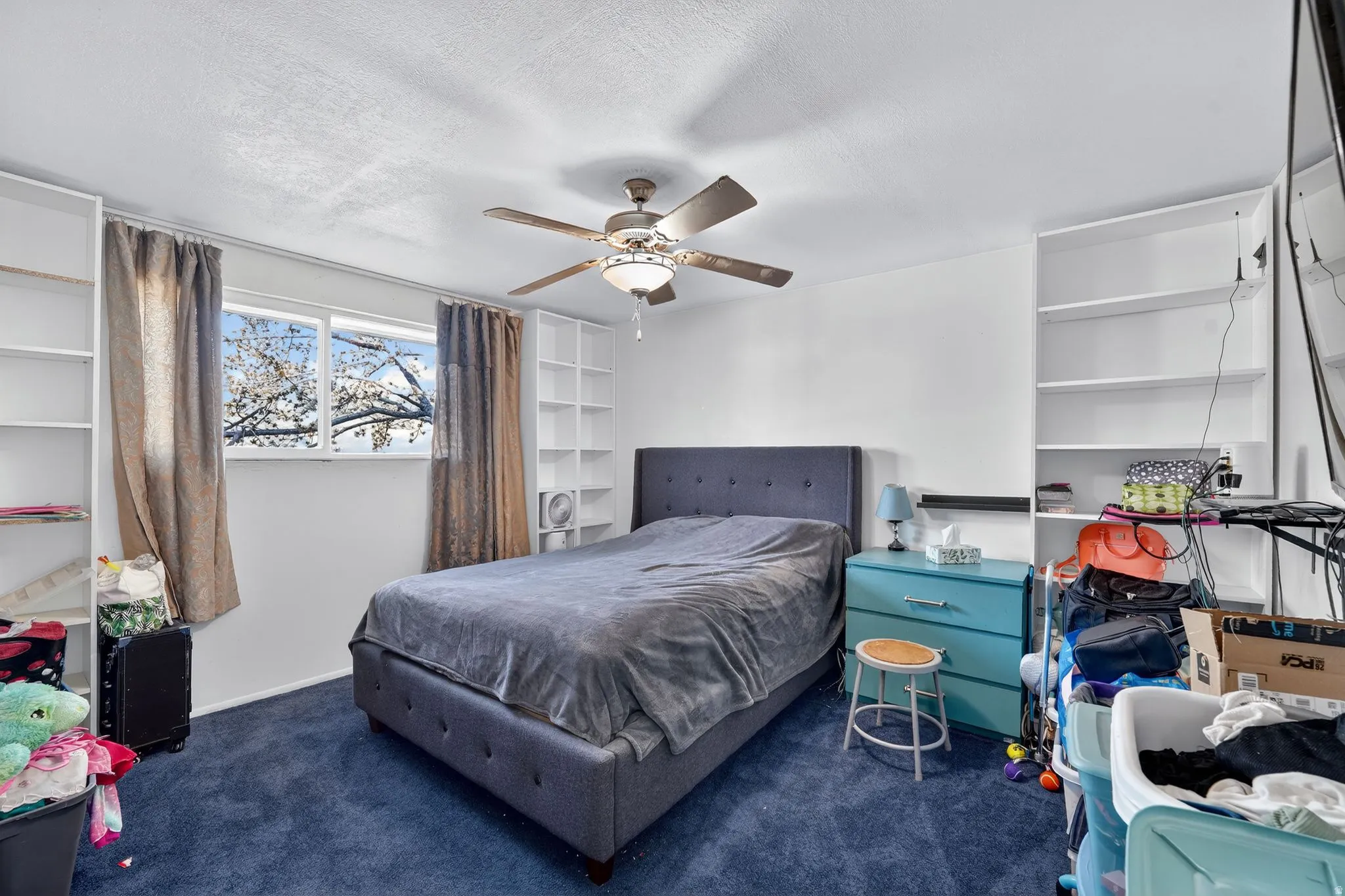 Bedroom with ceiling fan, and a textured ceiling