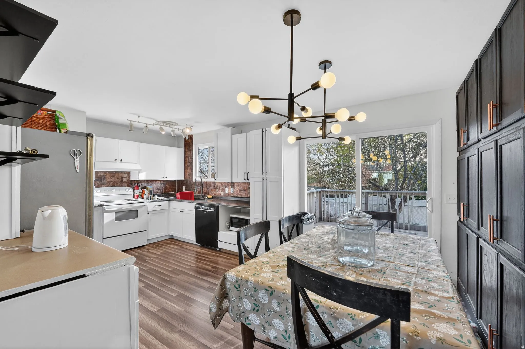 Kitchen with white electric range oven, laminate flooring, freestanding refrigerator, hanging lights, and extractor fan