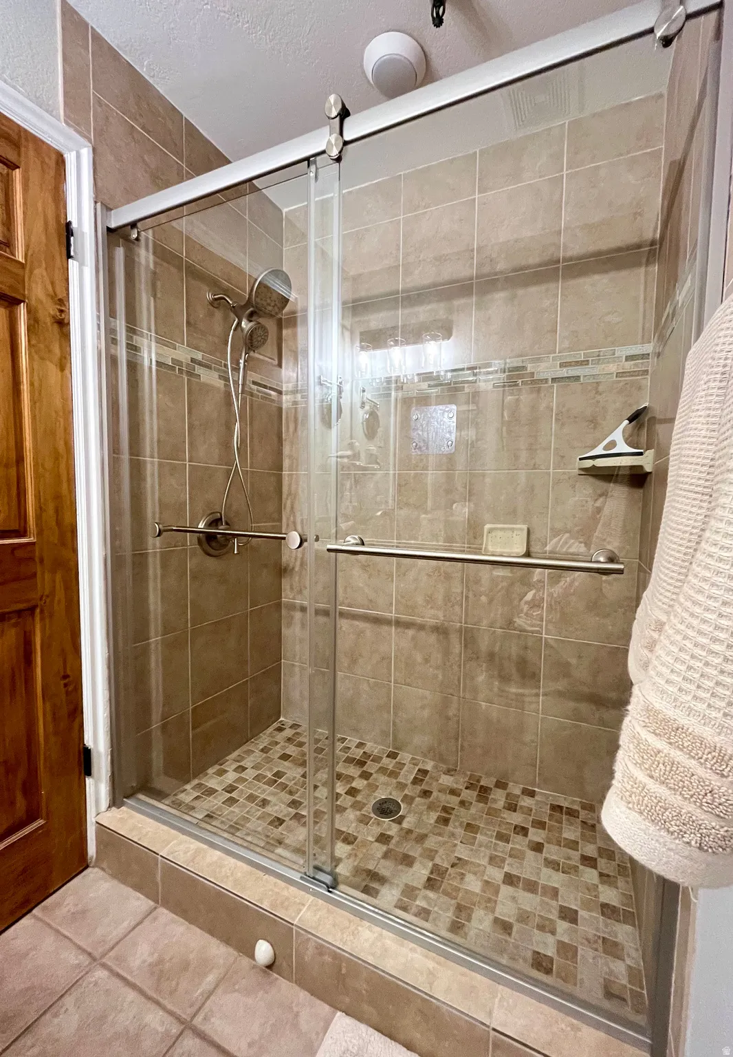 Bathroom with a textured ceiling, a stall shower, and tile patterned floors