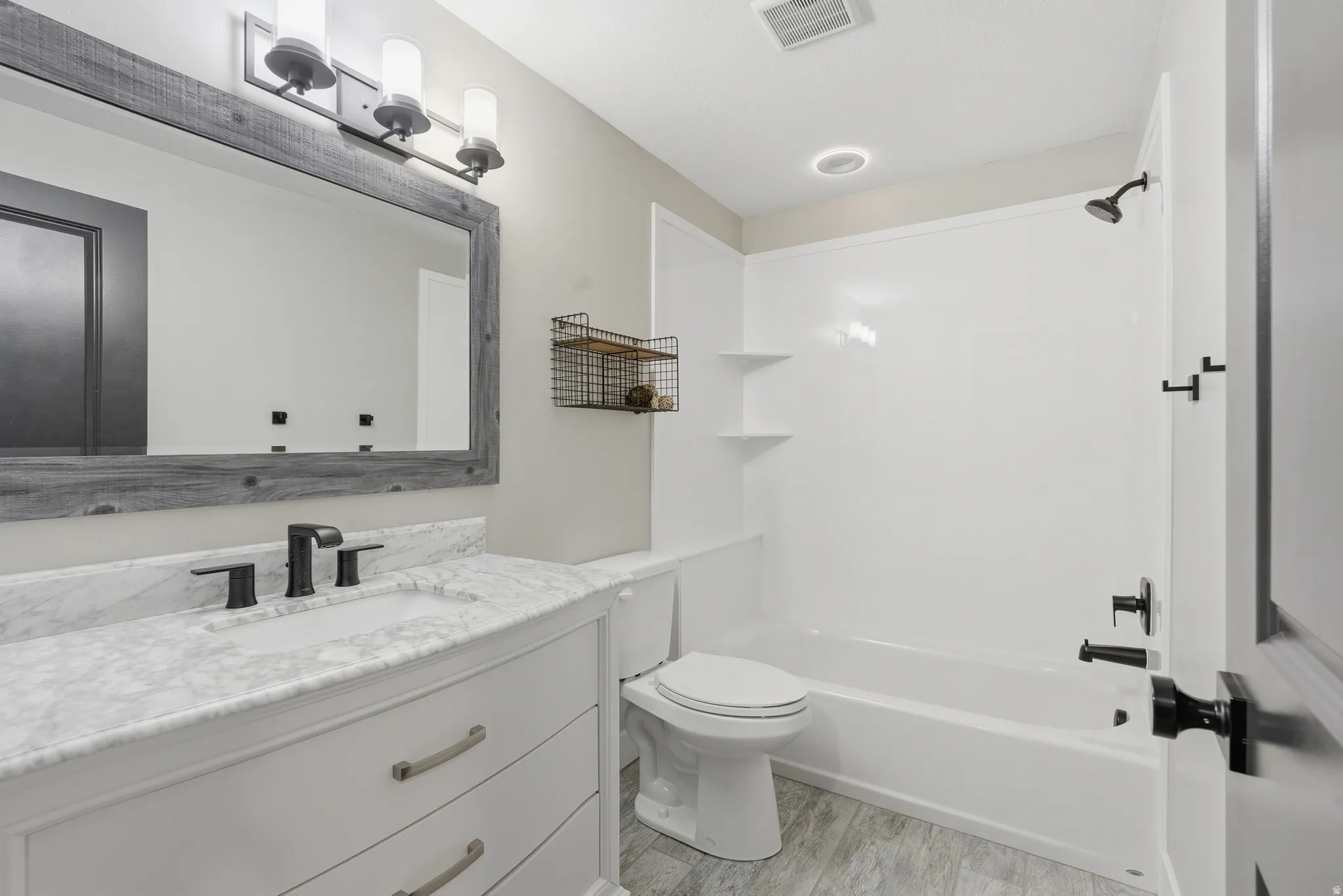 Bathroom with vanity, washtub / shower combination, and light wood-style floors
