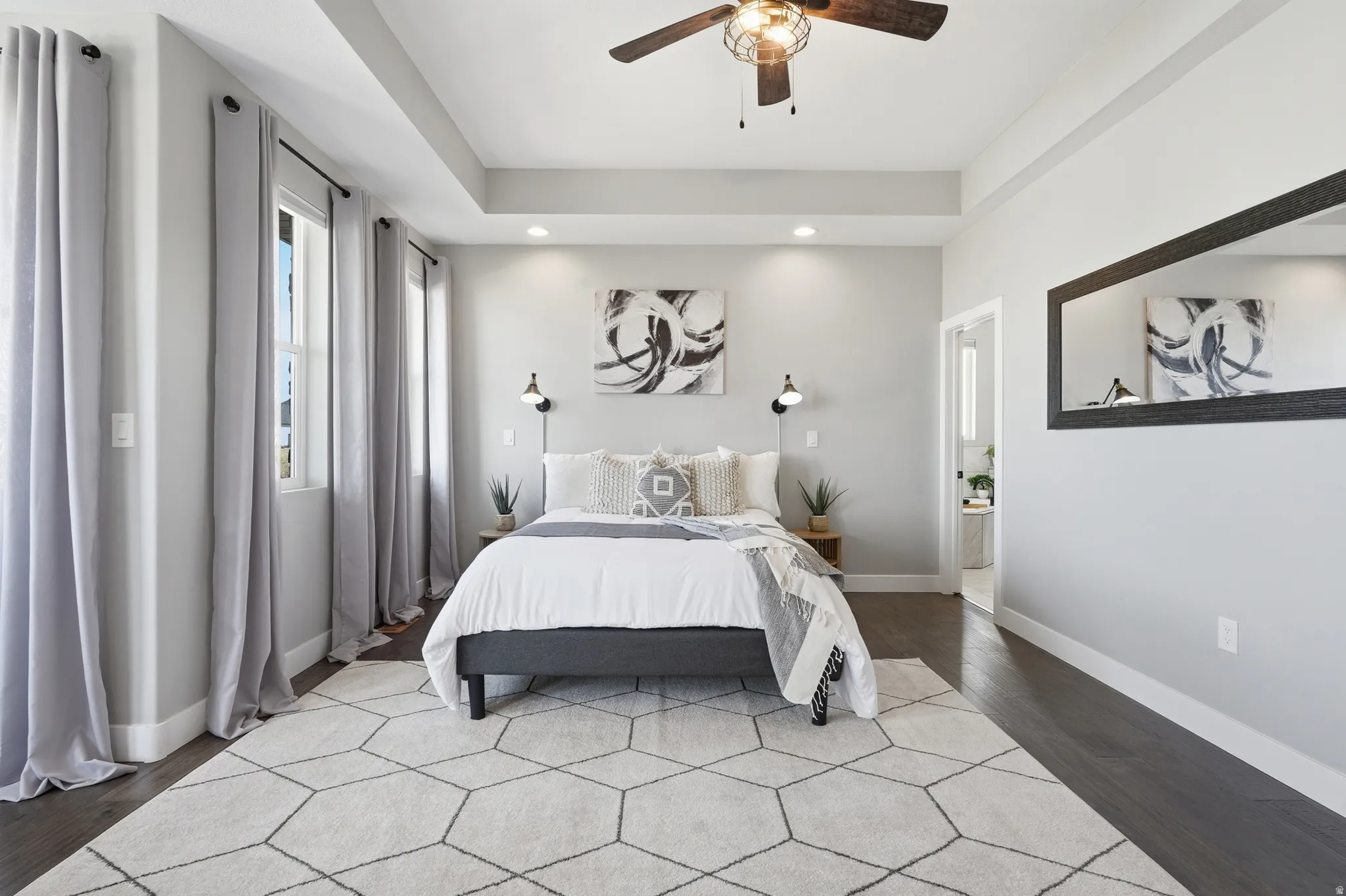 Primary bedroom featuring recessed lighting, wood finished floors, a ceiling fan, and a raised ceiling