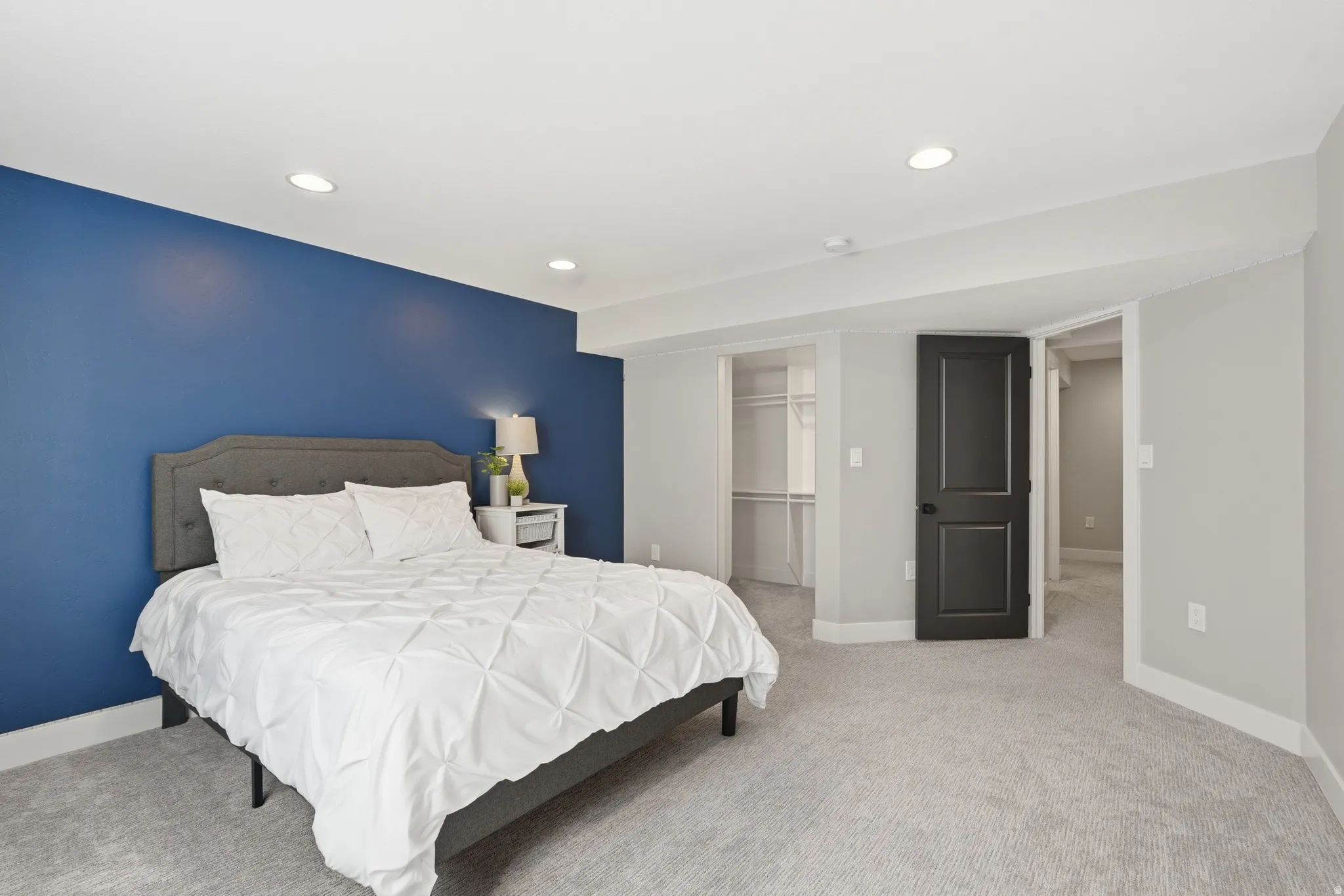 Bedroom featuring a walk in closet, light carpet, and recessed lighting