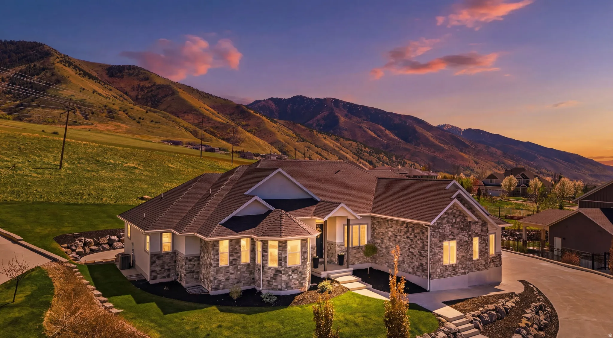 View of front of house featuring a lawn, stone siding, a mountain view, and driveway