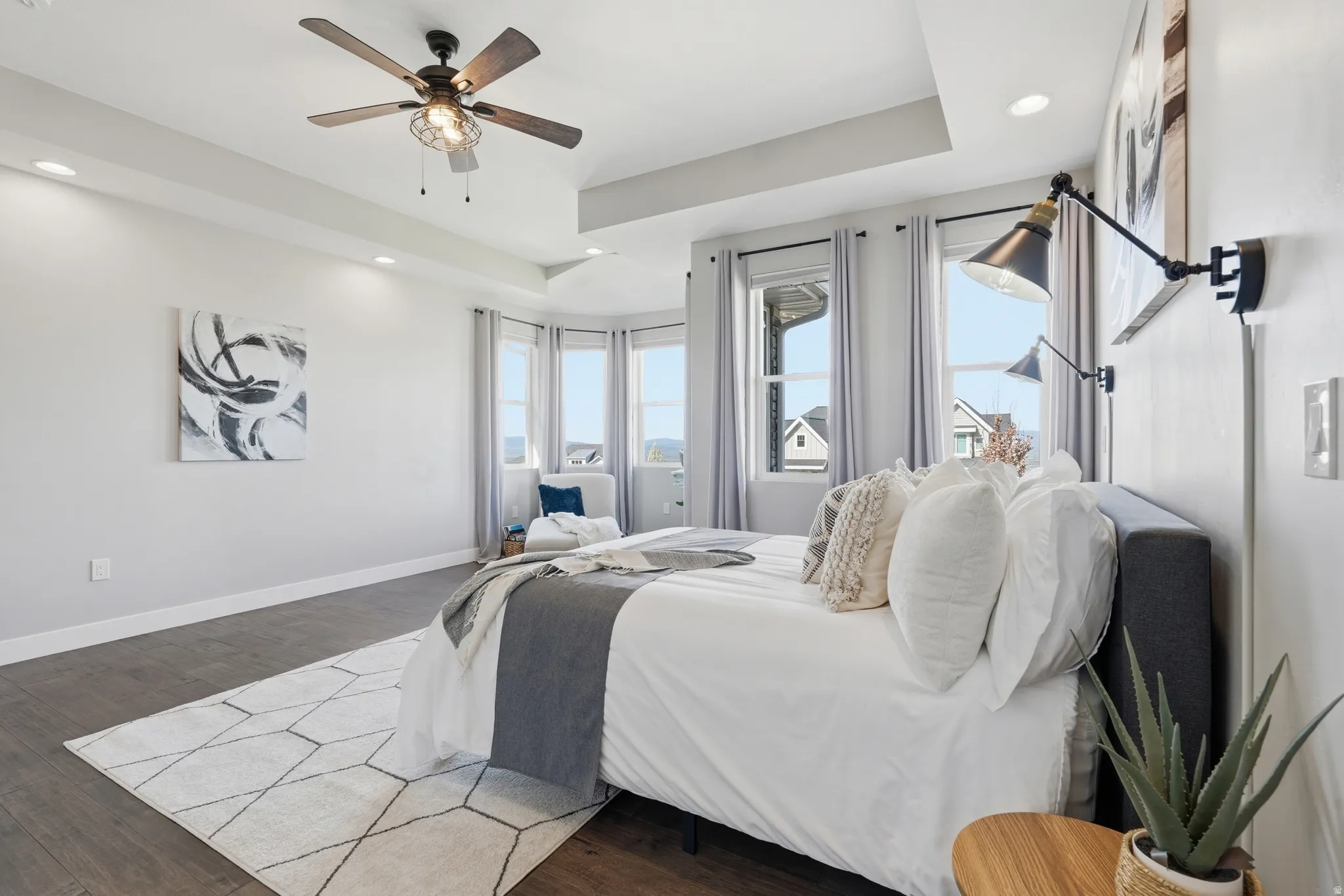 Primary bedroom featuring a tray ceiling, wood finished floors, recessed lighting, and ceiling fan