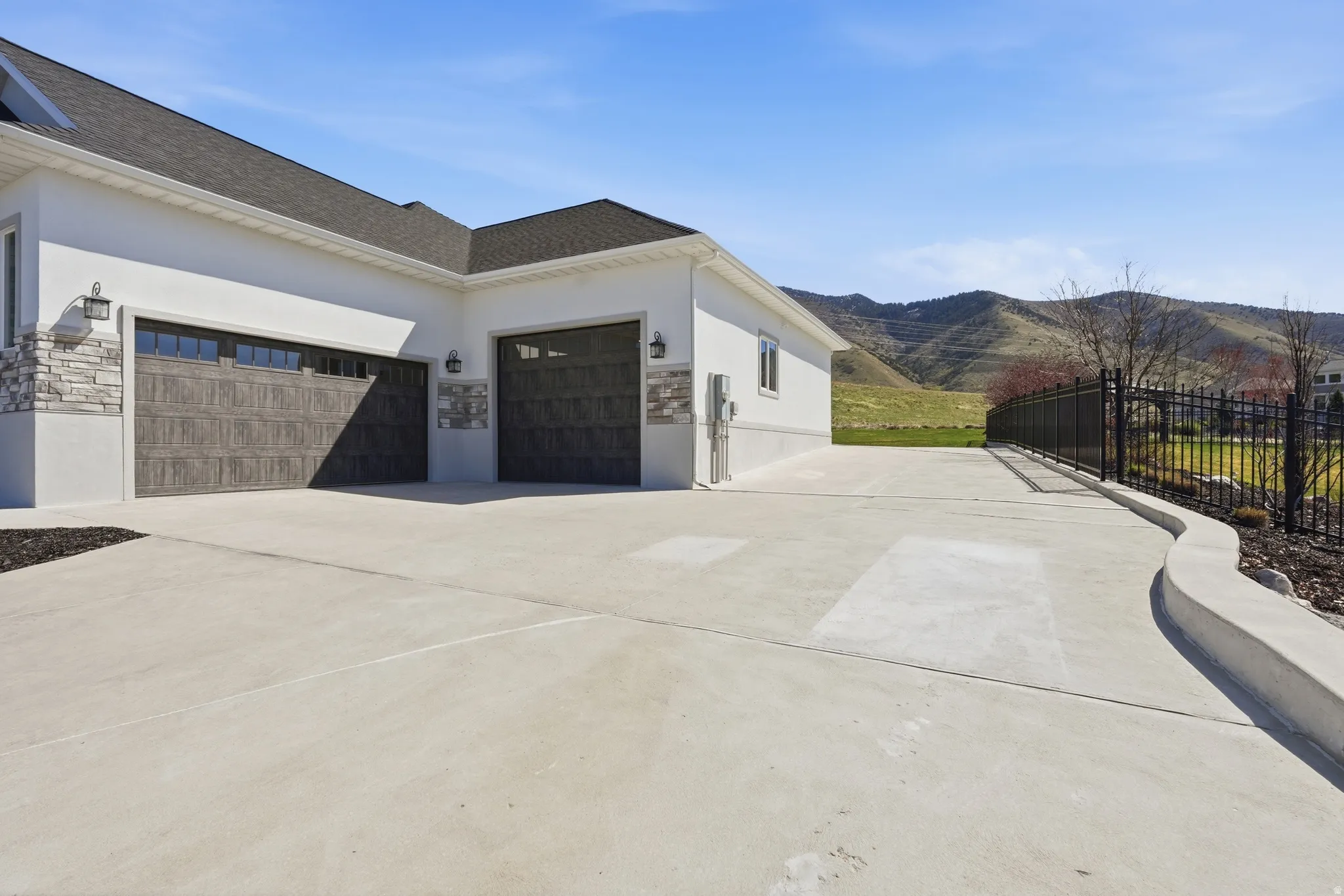 View of property exterior with stone siding, stucco siding, a garage, and concrete driveway for extra parking