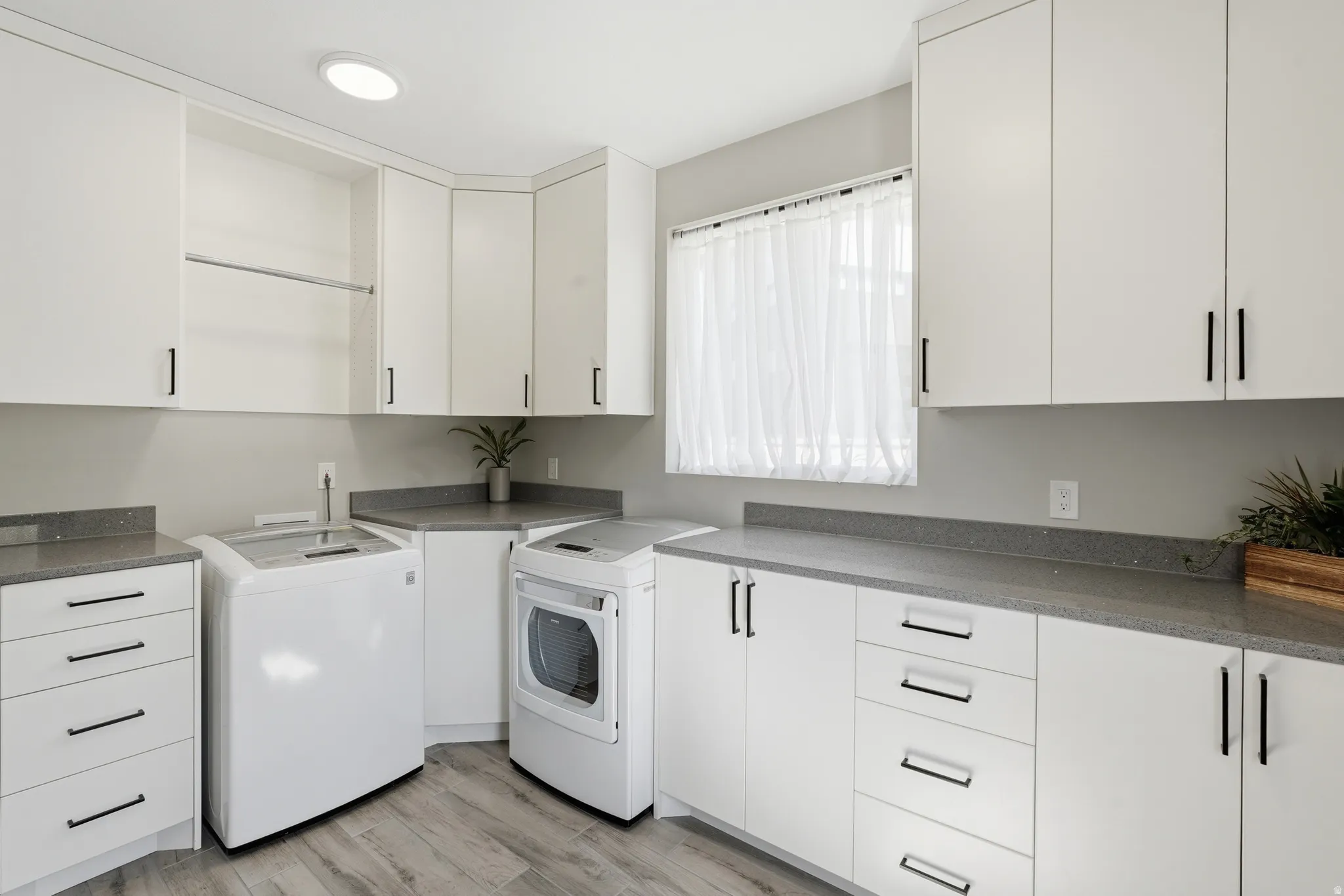 Laundry room featuring light wood-style floors, separate washer and dryer, cabinet space, and recessed lighting