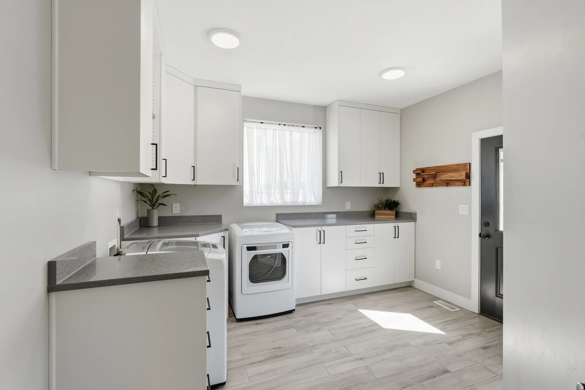 Laundry area with cabinet space and light wood-type flooring