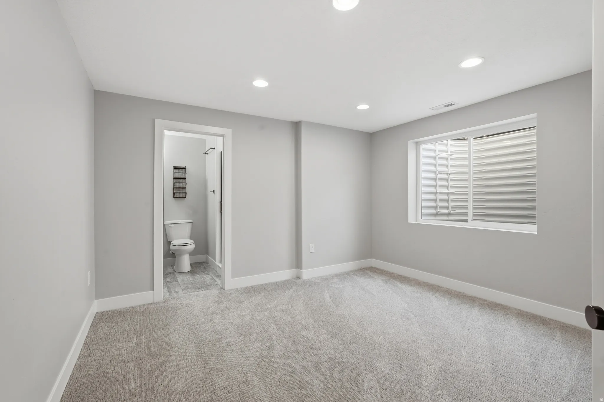 Unfurnished bedroom with recessed lighting, light carpet, and ensuite bath